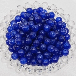 Macro view of blue glass beads with central drill holes in a clear glass dish
