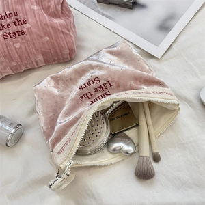 Vista dettagliata della borsa cosmetica in velluto rosa aperta con ricamo stelle