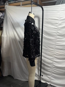 Detail view of shimmering black sequins and button-down collar on long sleeve shirt
