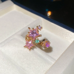 Macro shot of gold star-shaped ring with pink and purple zircon gemstones on white velvet
