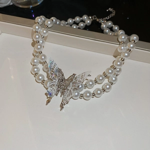 Detail of double-layer pearl necklace featuring a shimmering silver butterfly pendant