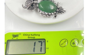 Detailed view of owl brooch pendant featuring a green gemstone weighing 17 grams