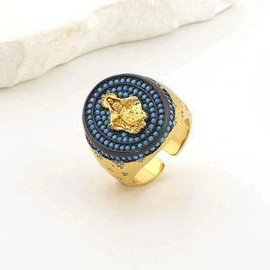 Detailed view of gold Mary medal ring featuring blue beads and black enamel center
