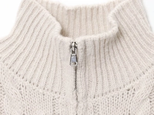 Detail of metal zipper and chunky knit texture on beige high-neck cardigan sweater