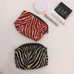 Detail of boat-shaped zebra pattern makeup bags with soft knit texture and zipper close