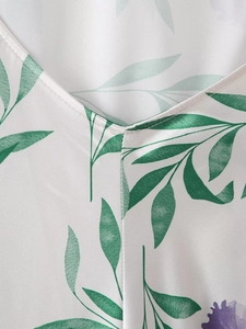 Détail du décolleté en V sur robe en soie blanche avec motif de feuilles vertes et couture