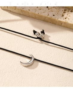 Detailed view of silver moon pendant on a black adjustable woven rope with metallic beads