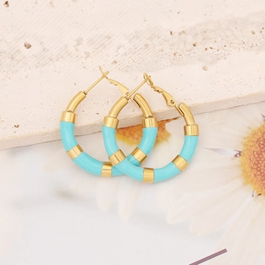 Macro detail of gold and sky blue enamel dripping earrings on marble background