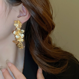 Detail of elegant gold layered flower petal earrings showing metallic texture on model