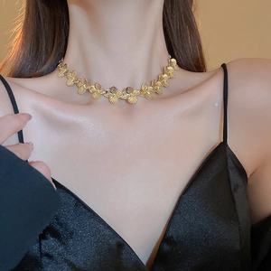 Elegant gold clover flower necklace worn by model showing delicate floral pendant details