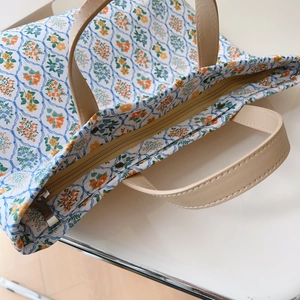 Gros plan du sac en coton fleuri avec fermeture éclair en métal et anses en cuir