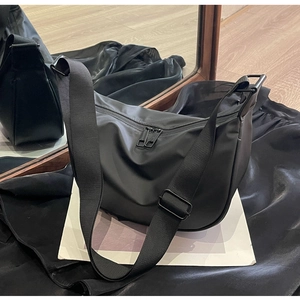 Detail of black nylon dumpling bag with dual zippers and adjustable wide shoulder strap