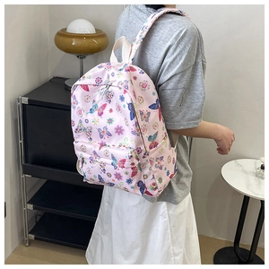 Dettaglio dello zaino rosa con stampe di farfalle colorate indossato da una modella