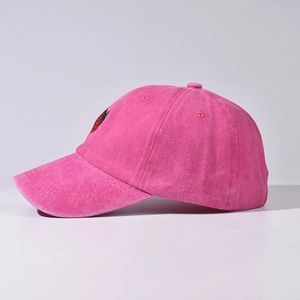 Dettaglio laterale di un berretto da baseball in cotone lavato rosa con fragola