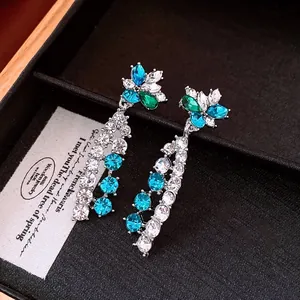 Detail of vintage flower pendant earrings with blue crystals and long silver tassels