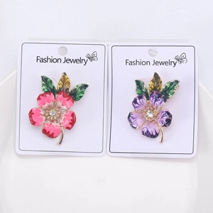 Detail of pink and purple enamel flower brooches with crystals on white display