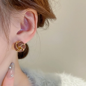 Close-up of vintage twist knot earring featuring red-brown enamel and gold plating
