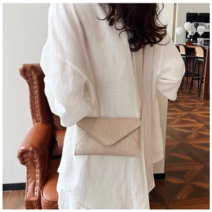 Modische goldene Pailletten-Umschlagtasche mit Metallkette, getragen von einem Model
