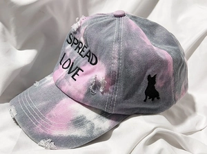 Macro view of Spread Love embroidery and bulldog patch on tie-dye baseball cap