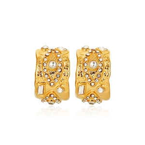 Close-up of vintage 18K gold C-shaped earrings with rhinestones and textured metal surface