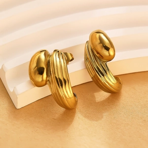 Gros plan détaillé de boucles d'oreilles dorées texturées sur un support blanc