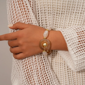 Detail of beaded bracelet with amber acrylic rings, cream beads and golden accents