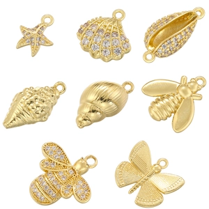 Macro shot of gold-plated seashell and starfish pendants with small inlaid gemstones