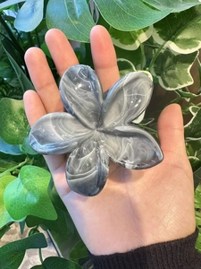 Détail d'une pince à cheveux fleur de 8cm avec texture marbrée grise sur fond de verdure