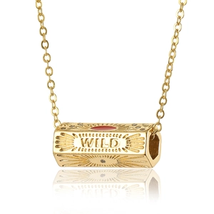 Macro shot of gold pendant with WILD engraving and sunburst texture details