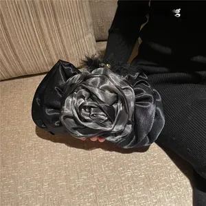 Macro shot of black satin evening clutch featuring handcrafted rose petals and feathers