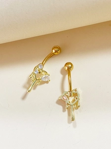 Detailed close-up of two golden heart-shaped belly rings set with pink zircons on beige base