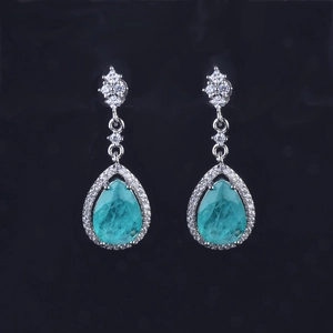 Close-up of luxury turquoise pear-cut earrings set in silver with sparkling stones