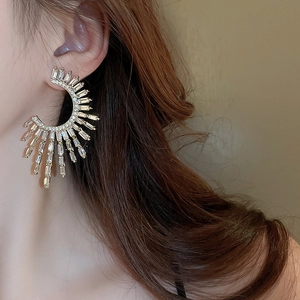 Macro detail of gold C-shaped earrings with square zircon stones on a female model