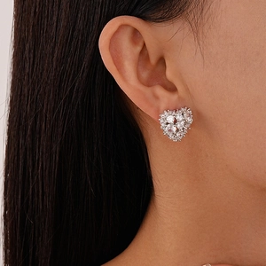 Close-up of heart-shaped zircon earrings with polished silver finish on ear