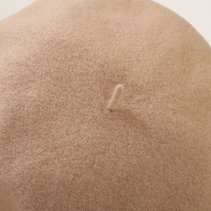 Macro detail of camel wool fabric texture and classic top stem on a retro beret hat