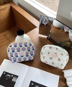 Quilted cotton cosmetic bags with purple floral and cherry patterns on a wooden table