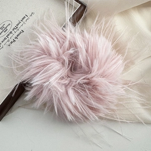 Detailed view of a soft grey-pink faux fur scrunchie with a fluffy feather texture