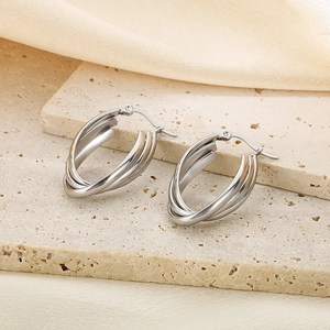 Detailed view of silver triple-layered interlocking oval hoop earrings on stone