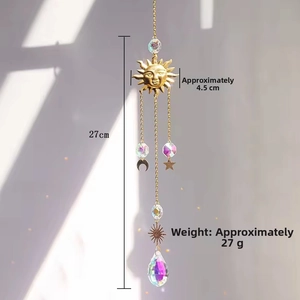 Detail of bohemian suncatcher with golden sun face, crystal prisms and moon charms