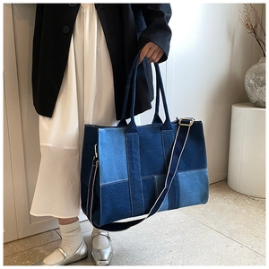 Detail of color-block denim tote bag with contrast stitching and detachable strap