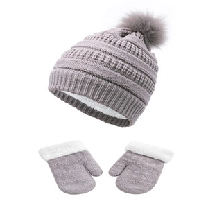 Detail of light grey knitted winter hat and gloves with soft white fleece lining