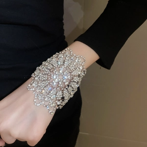 Detailaufnahme eines breiten, hohlen Blumenarmbands mit funkelnden Strasssteinen