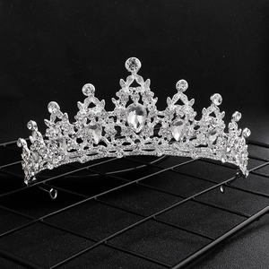Detailed close-up of a silver bridal crown with sparkling rhinestones on a dark stand