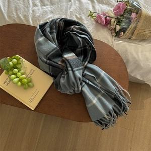 Close-up of classic plaid tassel scarf with soft cashmere-like texture on wooden table