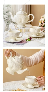 Close-up of vintage embossed ceramic teapot and cups set with lace and floral details