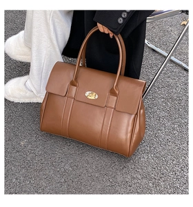 Top view of a large brown leather tote bag with metal buckle for autumn office wear