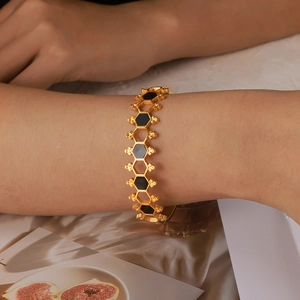 Vintage golden honeycomb bangle with black hexagonal acrylic inlay on woman's wrist