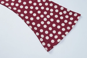 Detail of burgundy polka dot dress fabric showing fine double-needle stitching on the hem