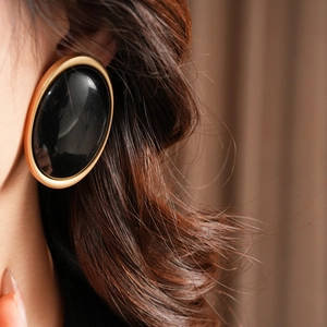 Close-up of vintage oval resin earring with matte gold metal edge on model's ear