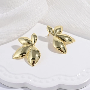 Boucles d'oreilles feuilles dorées à l'or 18 carats sur plateau blanc avec gaze